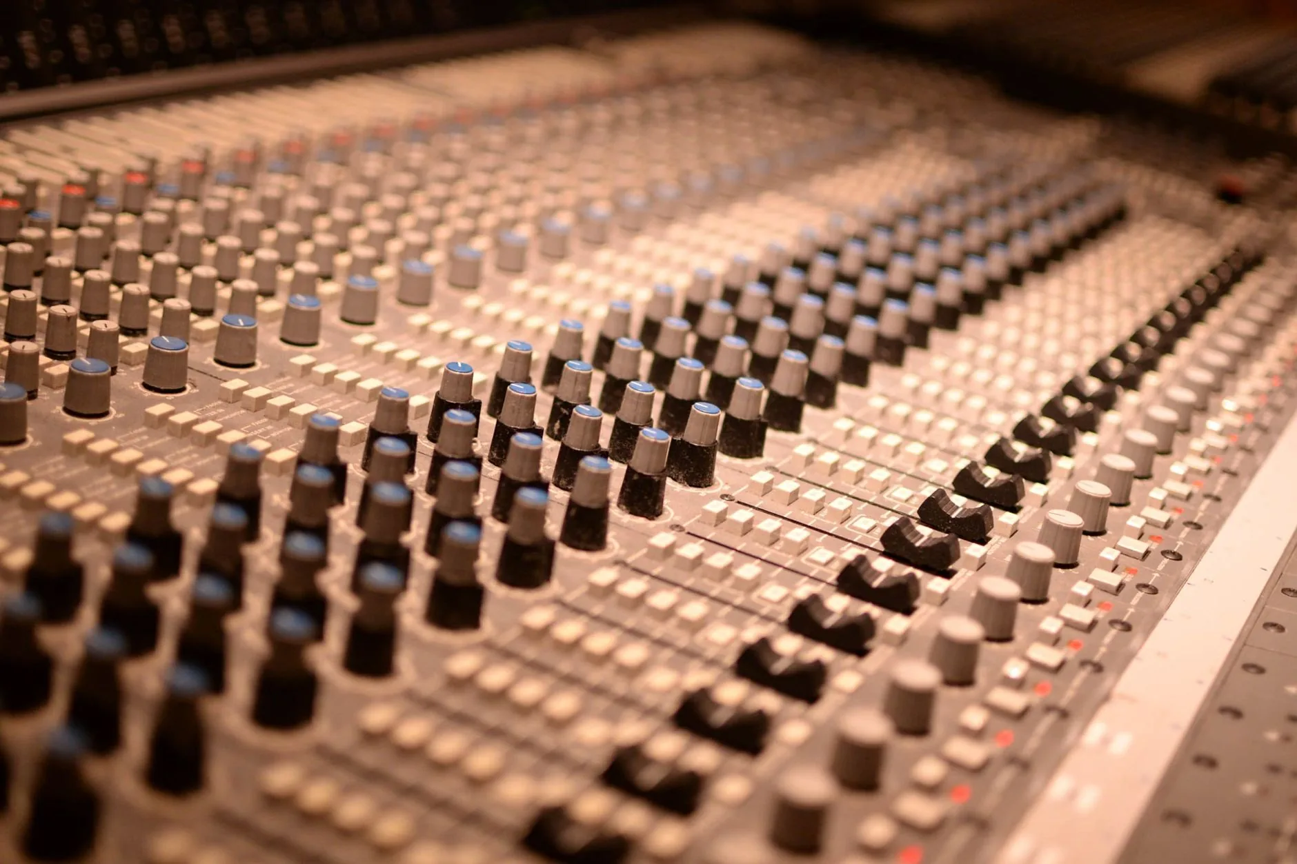Sound engineer in control room, hands over mixing board, dim lighting. Audio engineering.